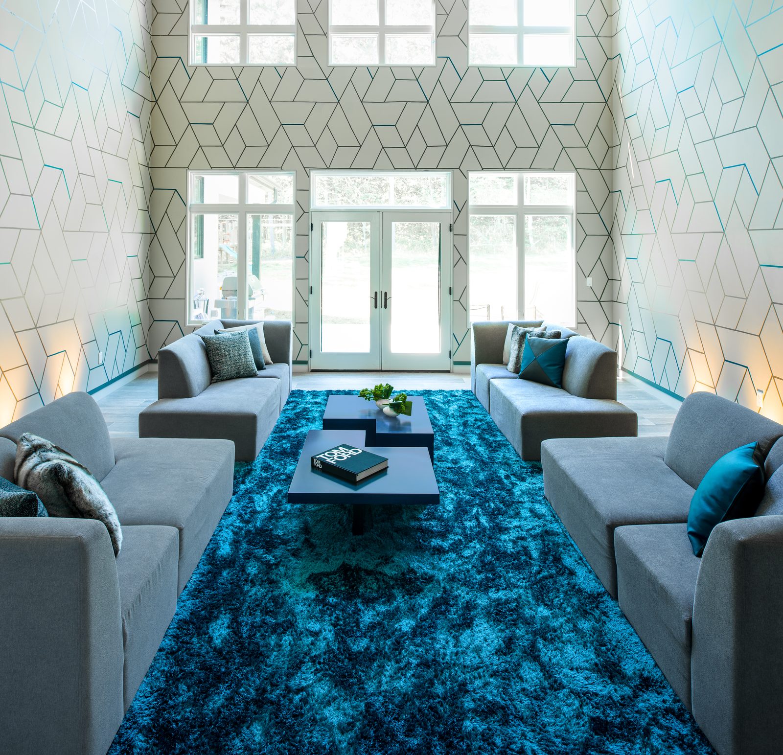 Double-height living room with geometric wallpaper and teal rug
